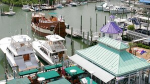A marina with boats docked, a covered seating area with tables and chairs, and a building with a green roof.