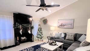 A living room with a fireplace, a Christmas tree, a sofa, and a coffee table.