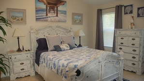 A bedroom with a bed, nightstands, a dresser, and artwork on the walls.