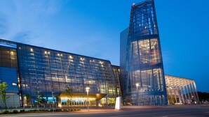 A modern glass building with a prominent vertical structure and a large entrance area.