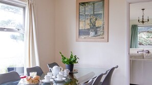 Enjoy meals in this cozy dining area with a glass table, teapot, and potted plant.
