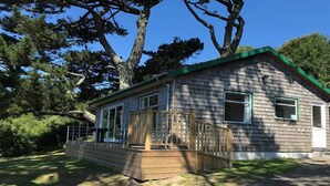 A small, single-story house with a green roof and a wooden deck. - Windwhistle - Two Bedroom Cottage, Sleeps 4 (Saint Martin-by-Looe)
