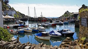 A harbor with various boats docked, rocky shore, and buildings in the background. - Windwhistle - Two Bedroom Cottage, Sleeps 4 (Saint Martin-by-Looe)