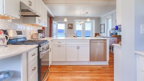 A modern kitchen with white cabinetry, a stainless steel stove, and a large island with a dishwasher.