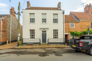 A two-story white building with a black door and windows, a paved driveway, and a parked black pickup truck. - Estcourt House, Burnham Market, Norfolk (Burnham Market)