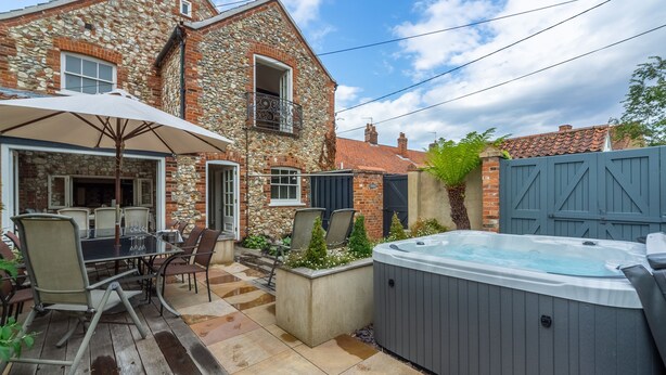 Una casa de piedra con un patio, mobiliario exterior y un jacuzzi.