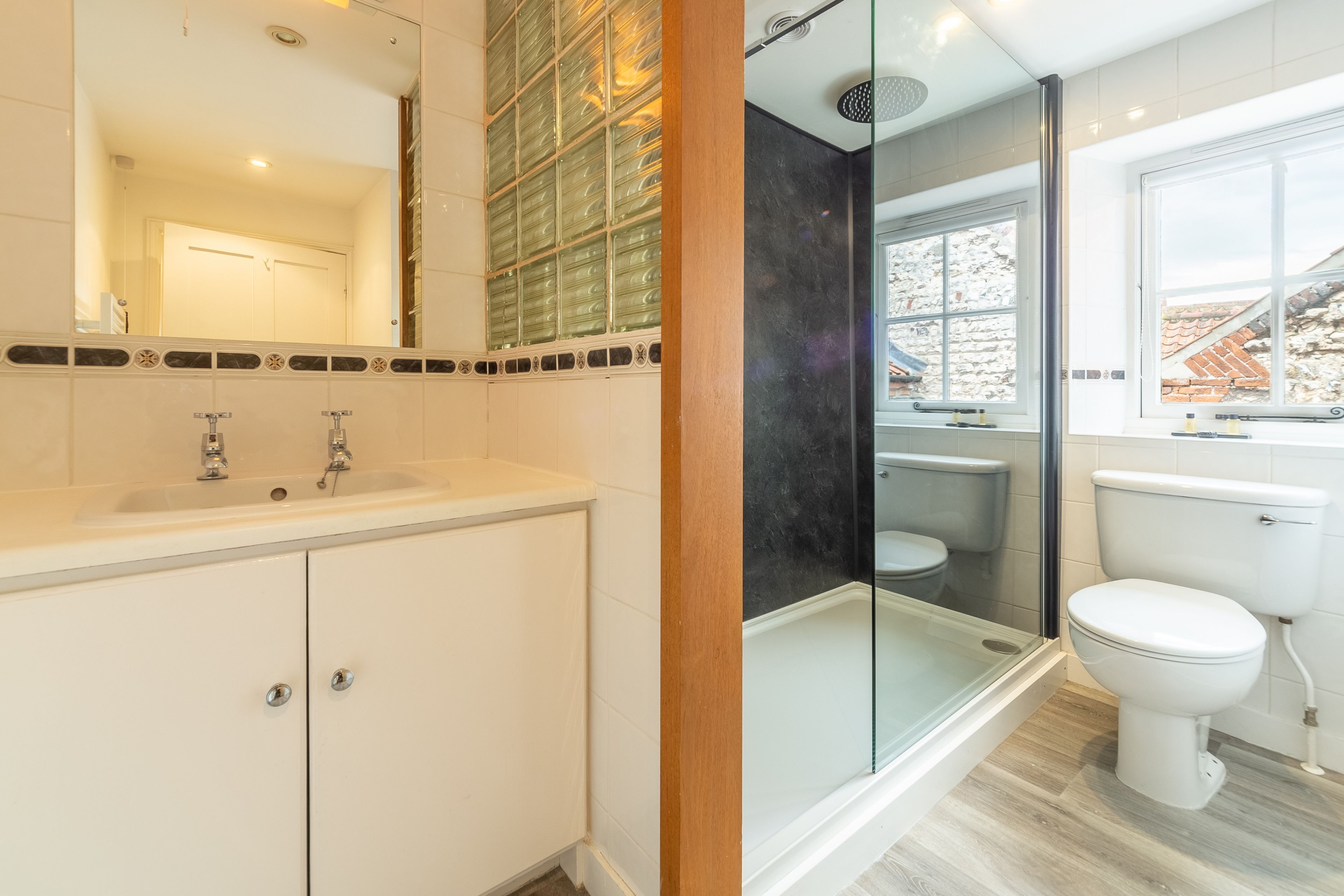A modern bathroom with a glass shower enclosure, a white sink, and a toilet.