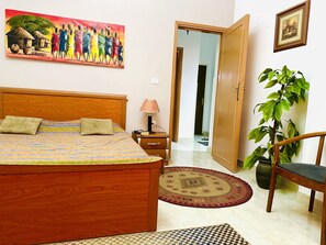 Cozy retreat with a comfortable bed, bedside table, and a lush potted plant.