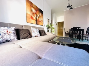 Relax in this stylish living room with a comfortable sofa, abstract art, and a glass coffee table.