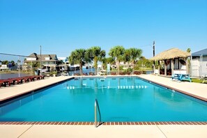 A swimming pool with a clear blue water, surrounded by a tiled deck and a few lounge chairs. - Beachfront Home with Beautiful Views (Galveston)