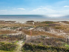 A coastal path leading to the beach with a wooden fence and sparse vegetation. - Beachfront Home with Beautiful Views (Galveston)