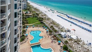 Ein Resort mit großem Poolbereich, einem Strand und einem Hochhaus.