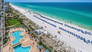 Ein Strandhotel mit Pool, Sonnenschirmen und freiem Blick auf den Ozean.