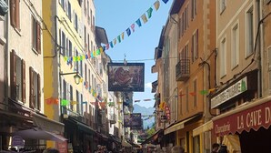 A cobblestone street lined with colorful buildings, a sign for 'La Cave D' Charcuterie, and a chalkboard menu. - Studio in the city center (Barcelonnette)