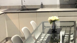 Una cocina moderna con microondas integrado, una mesa de vidrio con sillas y un florero con flores.