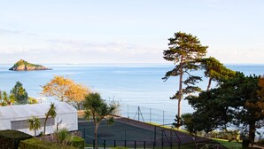 Ein Tennisplatz mit Blick auf das Meer und eine kleine Insel.