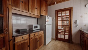 A kitchen with wooden cabinets, a microwave, and a refrigerator. - Large close to Downtown appartment (Ushuaia)