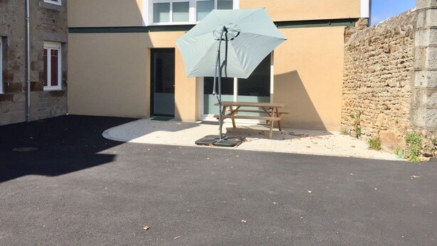 A house with a patio, a table, and an umbrella.