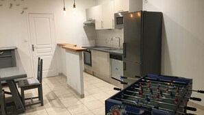 A modern kitchen with a foosball table, a dining area with a table and chairs, and a microwave above the counter.