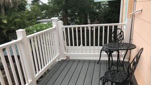 A wooden deck with a white railing, a round table, and two chairs. - COZY BEACH HOUSE 2 BEDROOM (Treasure island)
