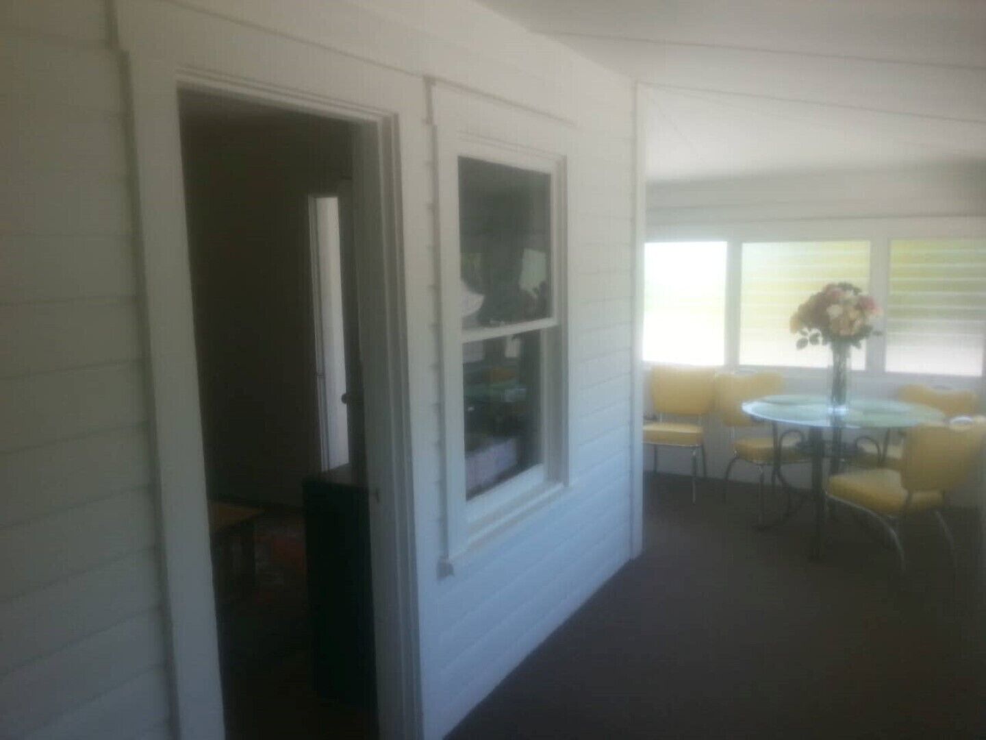 A room with a window, a door, and a small table with chairs.