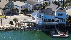 Una casa costera con un muelle, una playa y vista despejada al océano.