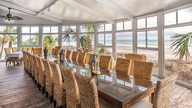 A long dining table with wicker chairs in a room with large windows overlooking the beach. - Two Bedroom Ocean View Luxury, Myrtle Beach 1751742 (North Myrtle Beach)