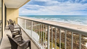 A balcony with chairs overlooking a beach. - Two Bedroom Ocean View Luxury, Myrtle Beach 1751742 (North Myrtle Beach)