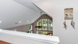 A modern interior with a staircase leading to a balcony overlooking a pool.