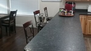 Una cocina con una encimera larga, armarios de madera, una pizarra y una cafetera roja.