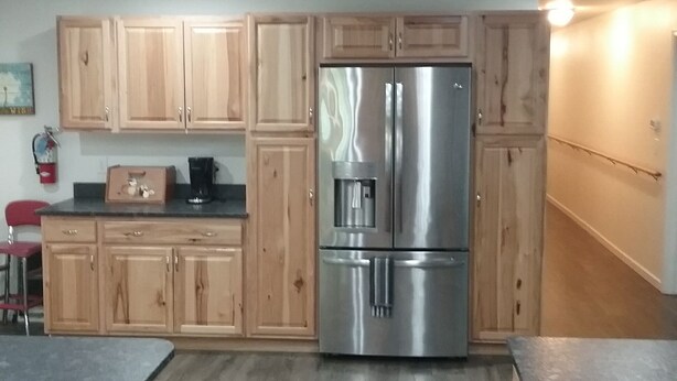 Una cocina con armarios de madera, un refrigerador de acero inoxidable, una cafetera y una silla roja.