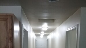Un pasillo estrecho con paredes blancas y puertas de madera a ambos lados.
