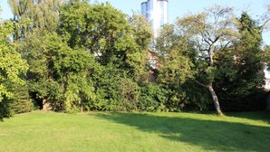 A grassy area with trees and a tall building in the background. - Holiday house in the center of Jever - In the house time-out, outside Frisian-tart (Jever)