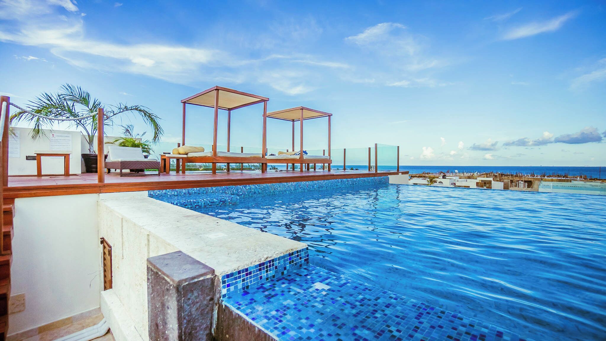 Ein Poolbereich mit Liegestühlen und Blick auf den Ozean.