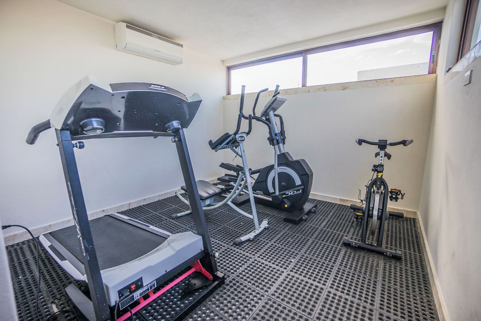 Ein Fitnessraum mit Laufband, Crosstrainer und Ergometer.
