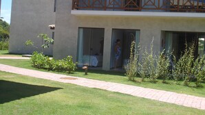 A two-story building with a balcony, a paved walkway, and a well-maintained lawn. - 3/4 Village in Quinta das Lagoas Reserva - Itacimirim Beach  (Camaçari)