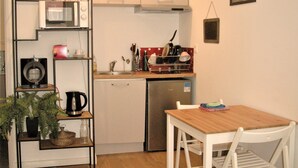 Cuina compacta amb microones, cafetera i taula petita de menjador amb cadires.