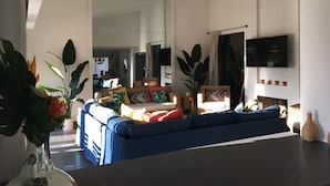 Ett modernt vardagsrum med en blå soffa, en platt-TV och en öppen spis.