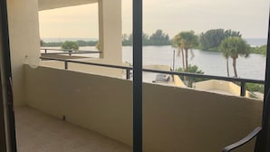 A balcony with a view of a body of water, a chair, and a rug. - Paradise Island (Hudson)