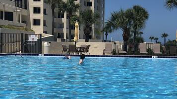 Une piscine à l’eau d’un bleu cristallin, entourée de chaises longues et de palmiers.