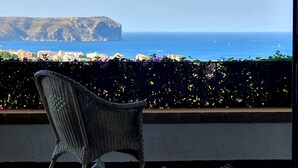 A wicker chair on a balcony overlooking a coastal cityscape with a prominent cliff and the sea. - Luxurious Villa Tosalet area with panoramic sea views (Jávea)
