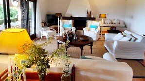 Ein geräumiges Wohnzimmer mit Kamin, weißen Möbeln und einem großen Fenster.