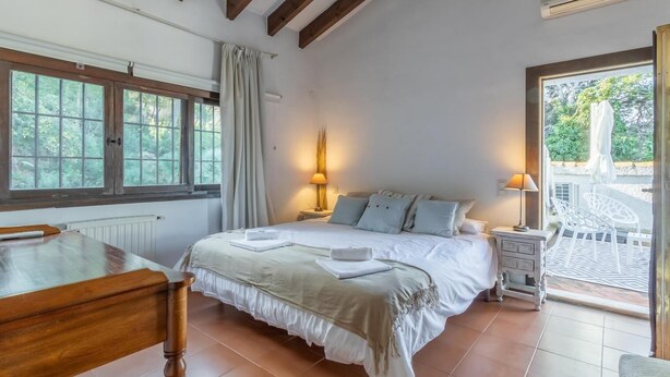 A bedroom with a bed, bedside tables, a wooden desk, and a view of the outdoors. - Luxurious Villa Tosalet area with panoramic sea views (Jávea)