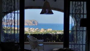 A balcony with a view of the sea and a mountain, furnished with wicker chairs and a hanging light fixture. - Luxurious Villa Tosalet area with panoramic sea views (Jávea)