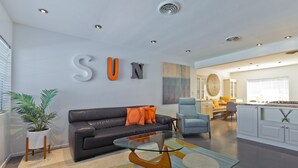 Ein modernes Wohnzimmer mit einer schwarzen Ledersofa, einem Glastisch und einem großen Wandzeichen mit der Aufschrift "SUN".