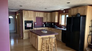 A kitchen with wooden cabinets, a black refrigerator, a microwave, and a sink. - Lake Superior Waterfront home (Brimley)