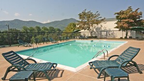 Una piscina con sillas de descanso y vistas a montañas.