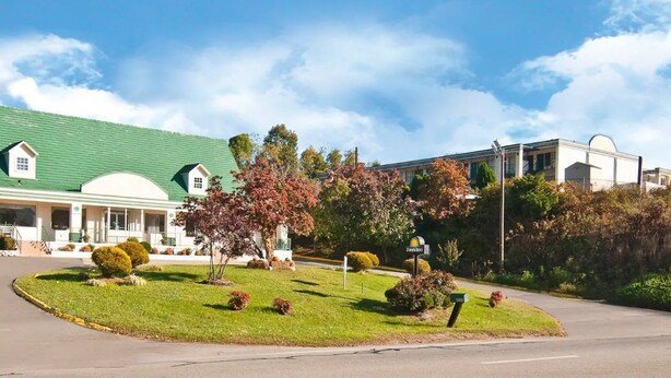 Un hotel con techo verde, zona exterior cubierta y jardines bien cuidados.