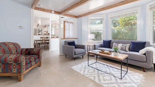 Una sala de estar con sofá, sillón, mesa de centro y una zona de comedor con sillas y mesa.