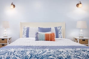 A neatly made bed with patterned bedding, two bedside lamps, and a headboard.